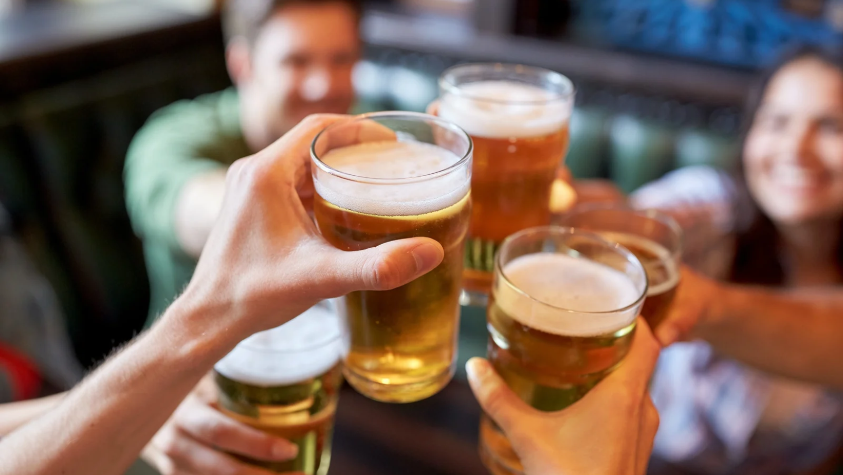 Group cheers with beer in restaurant booth.